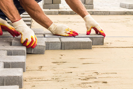 Workers laying paving tiles during construction