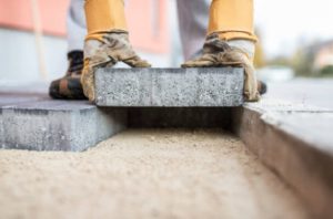 Inserting stone paver with gloved hands