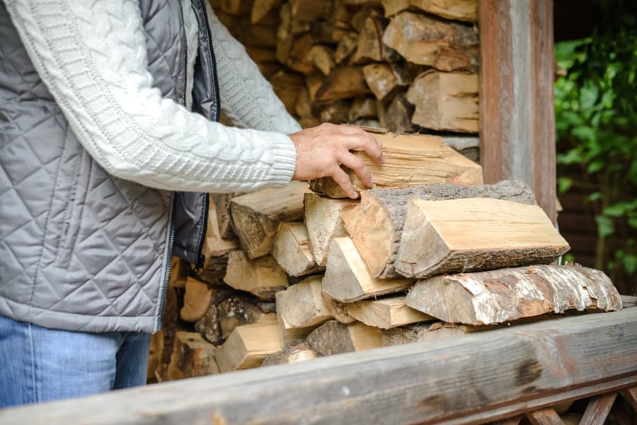 Hand grabbing firewood from stockpile