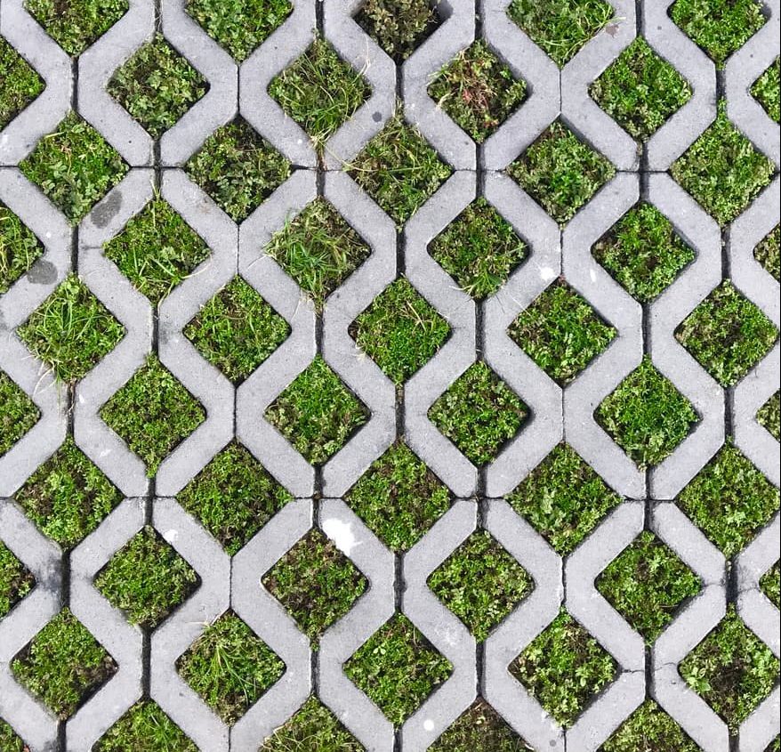 Overhead view of gray stone permeable pavers in diamond pattern with grass growing in between